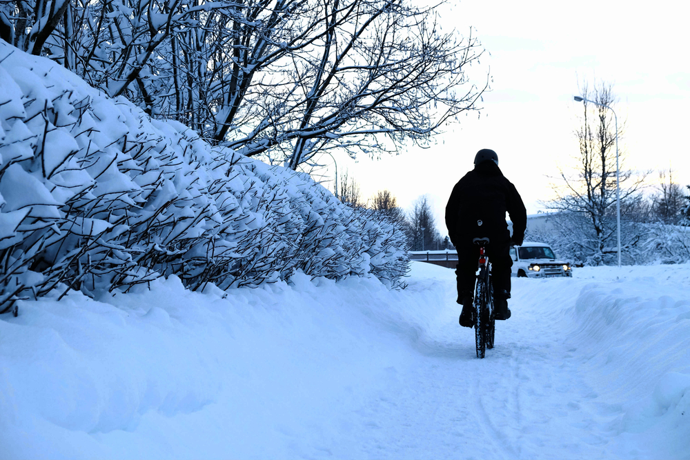 Man bikes along paved street in snow